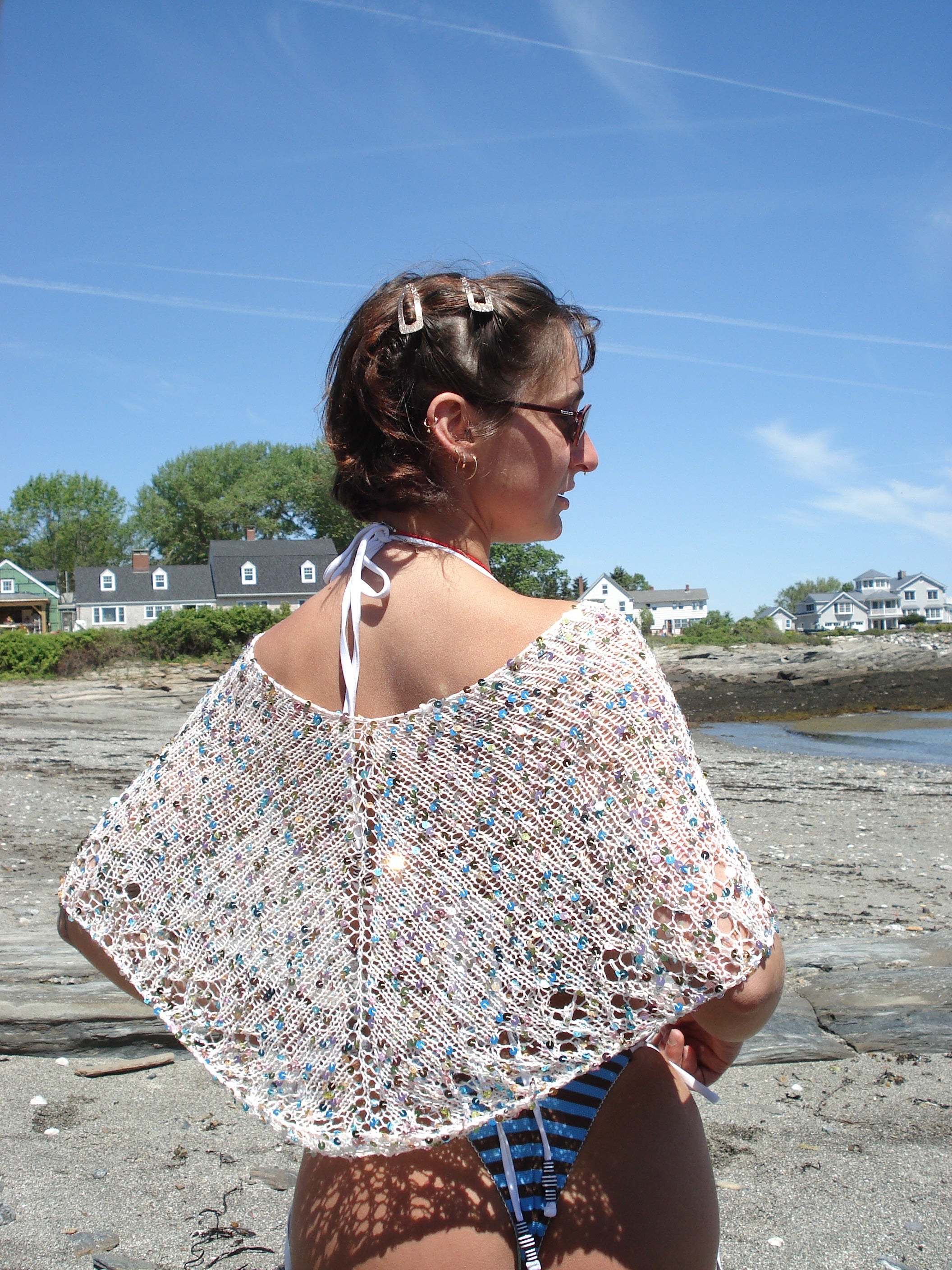 A woman wearing a colorful knit poncho on a beach
